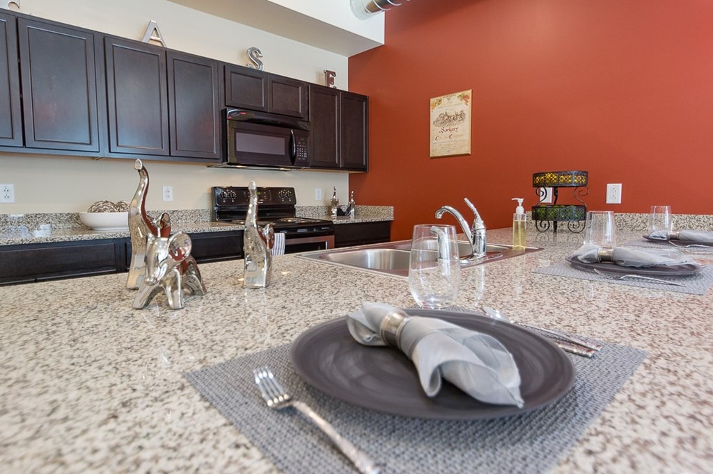 A kitchen with a red wall and a granite countertop.