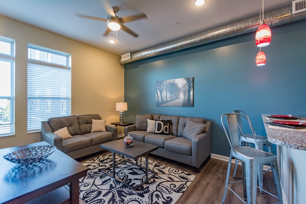 A living room with a grey couch, a coffee table, and a painting on the wall.