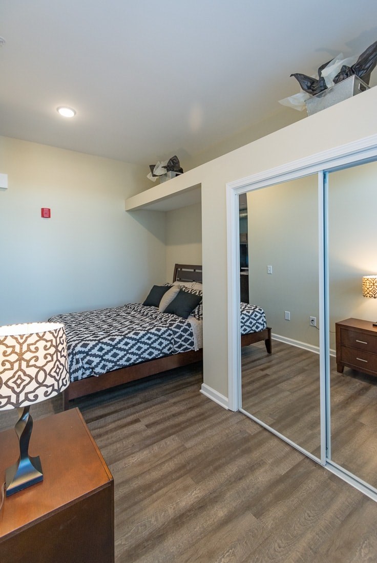 A bedroom with a bed, nightstand, and a ceiling fan.