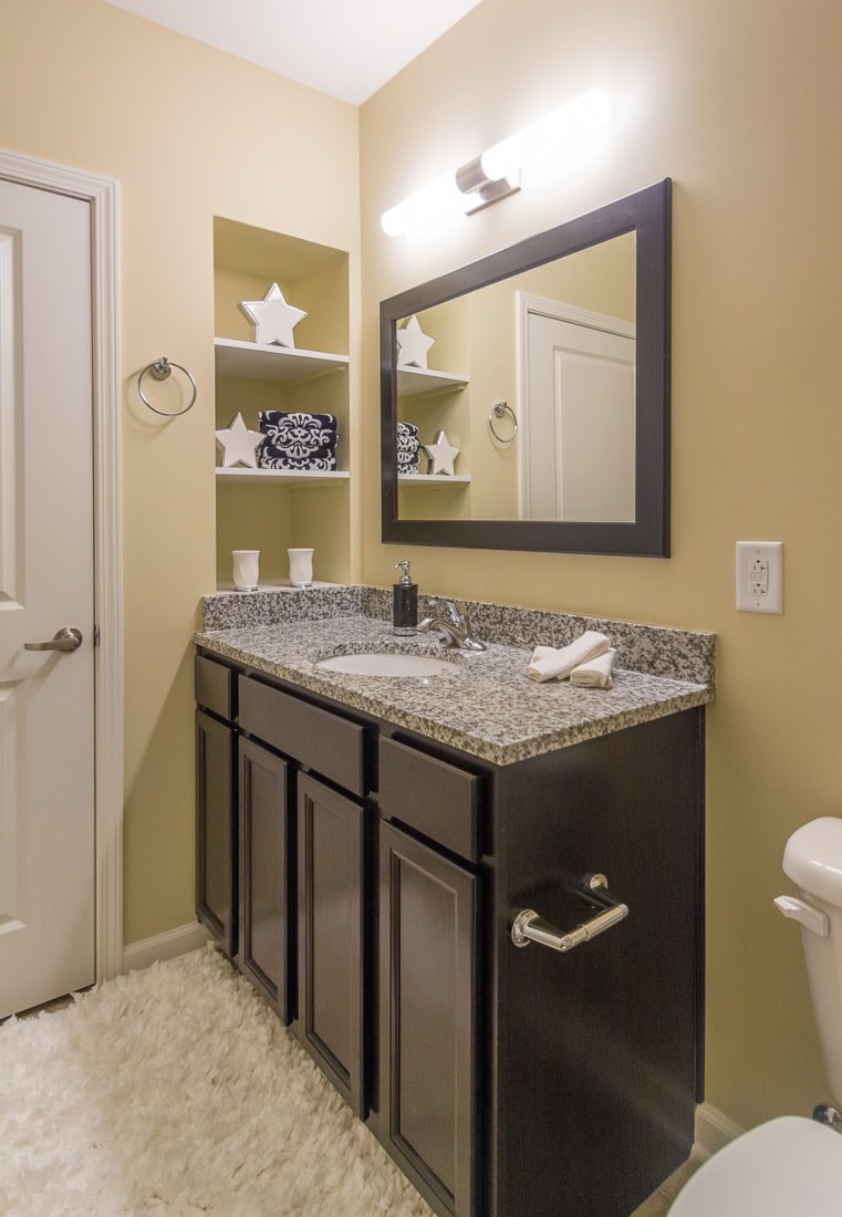 A bathroom with a black vanity and a mirror above it.