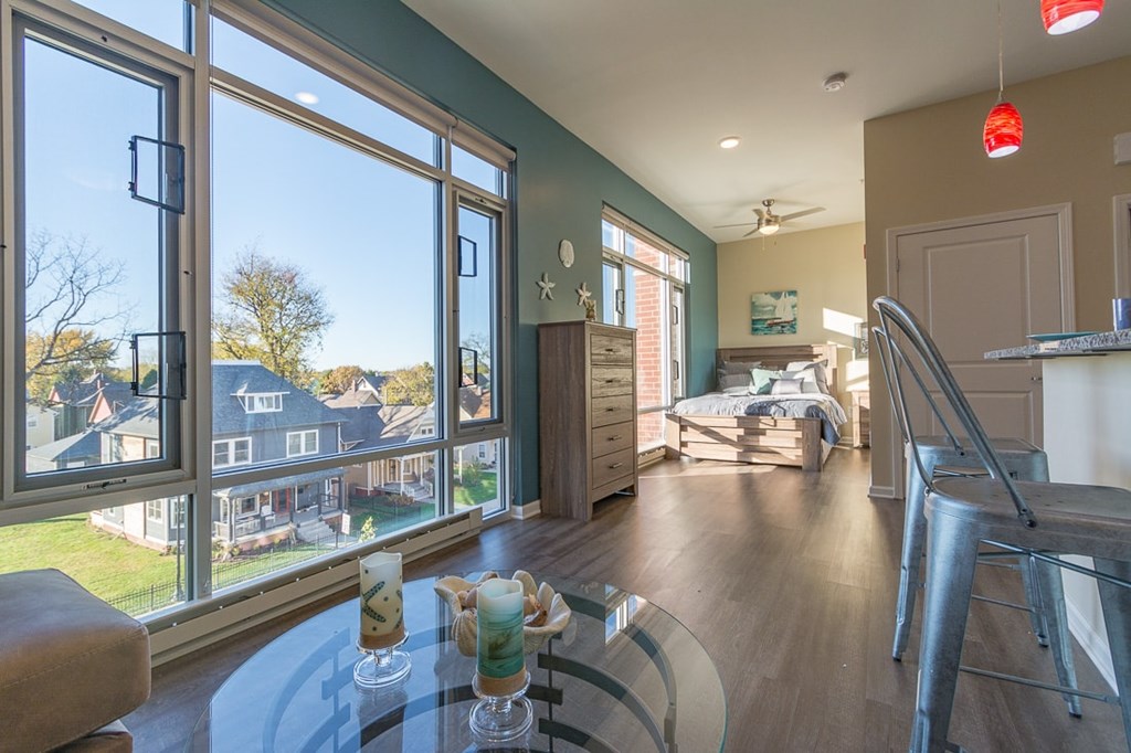 A dining table with candles on it in a room with a view of houses across the street.