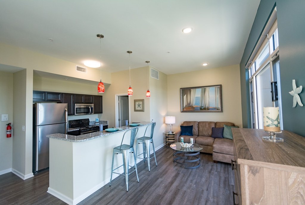 A modern kitchen with a bar area and a living room area.