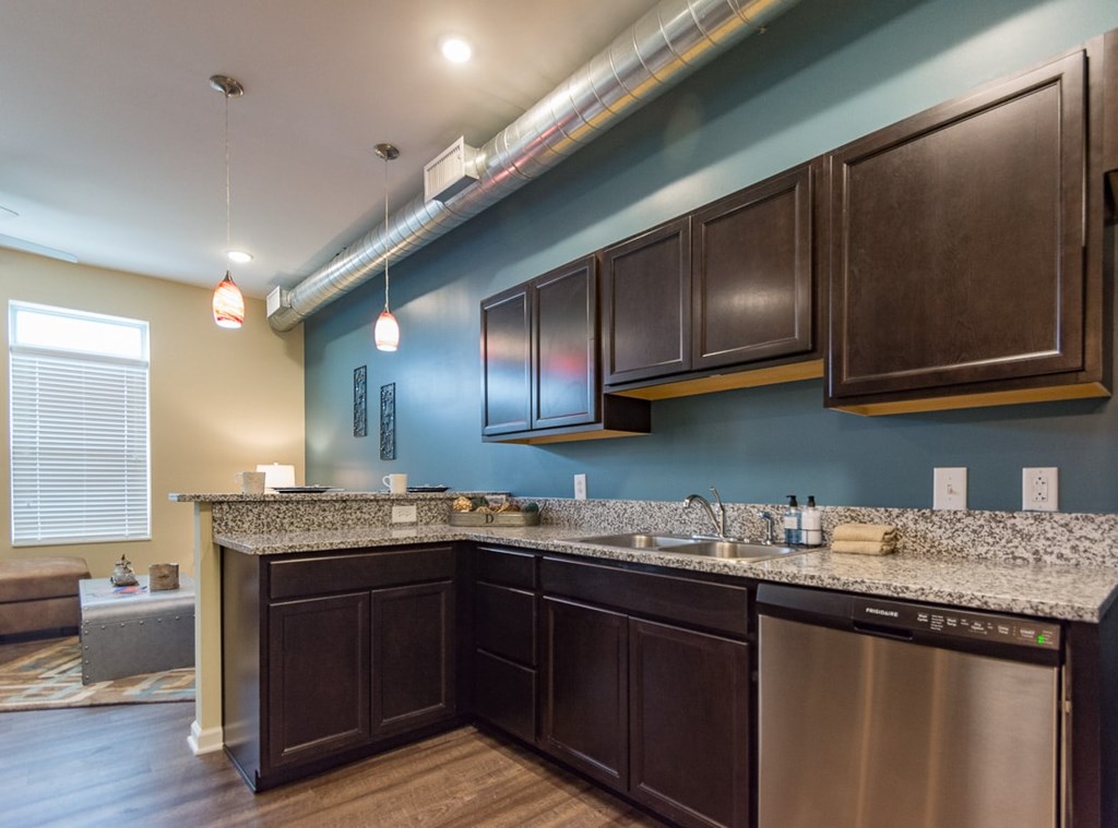 A kitchen with dark brown cabinets and a granite countertop.