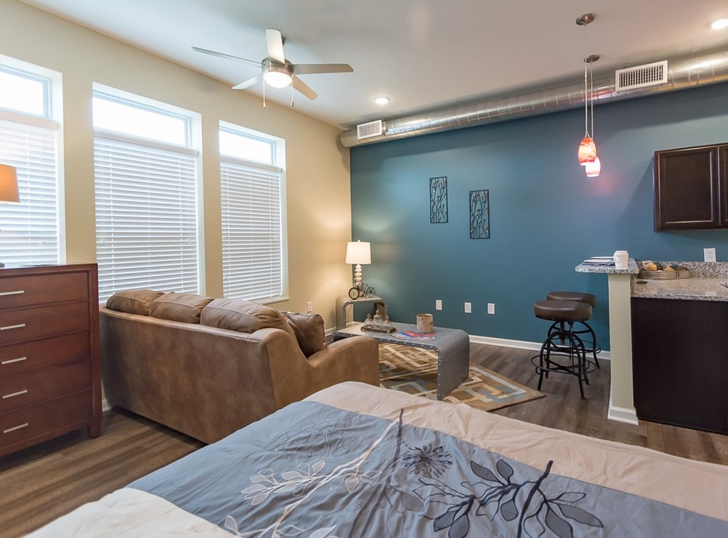 A bedroom with a bed, couch, and a ceiling fan.