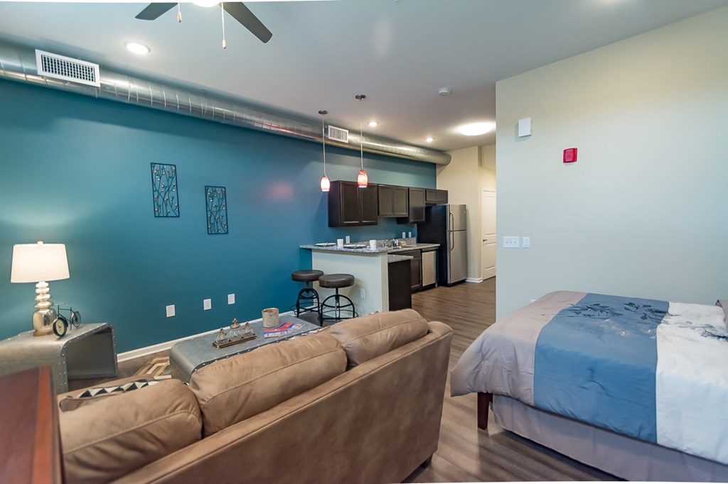 A living room with a brown couch and a blue bed.
