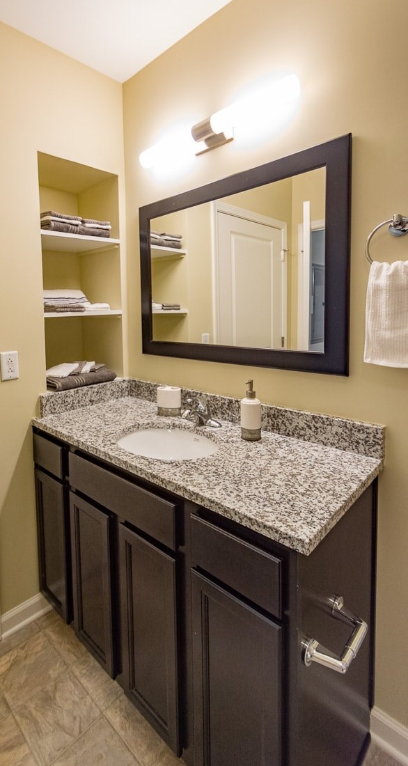 A bathroom with a sink, mirror and towel rack.
