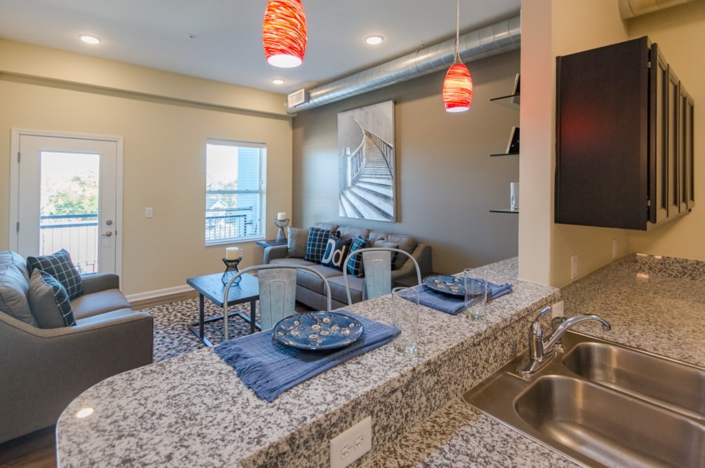 A kitchen with granite countertops and a dining area with a couch and chairs.