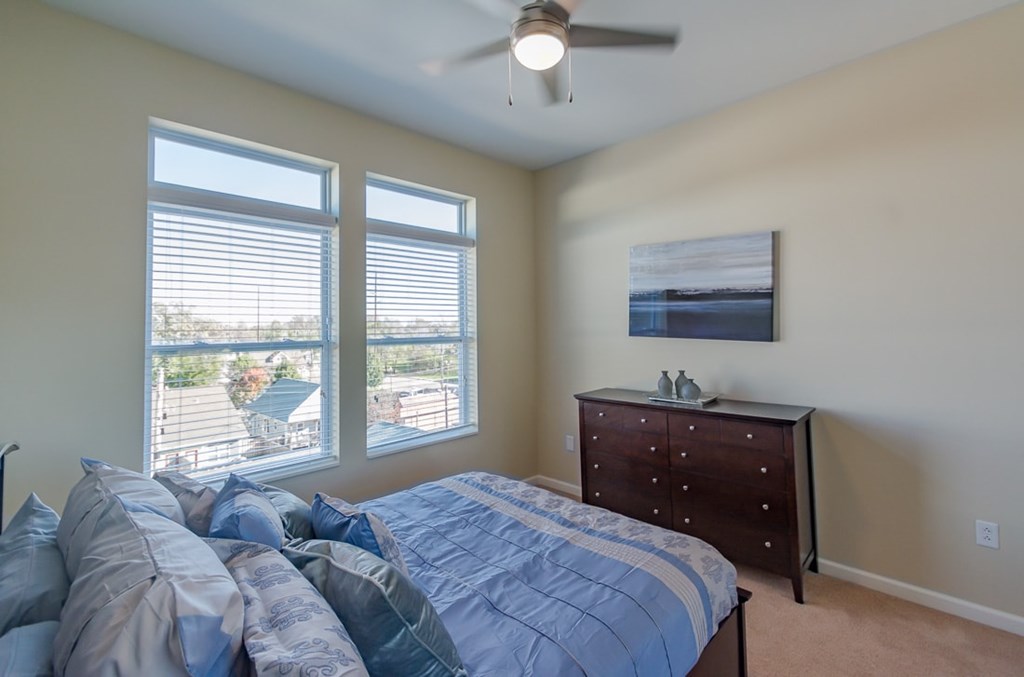 A bedroom with a bed, dresser, and a painting on the wall.