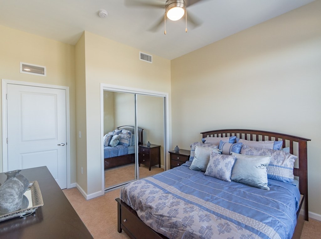 A bedroom with a bed and a ceiling fan.