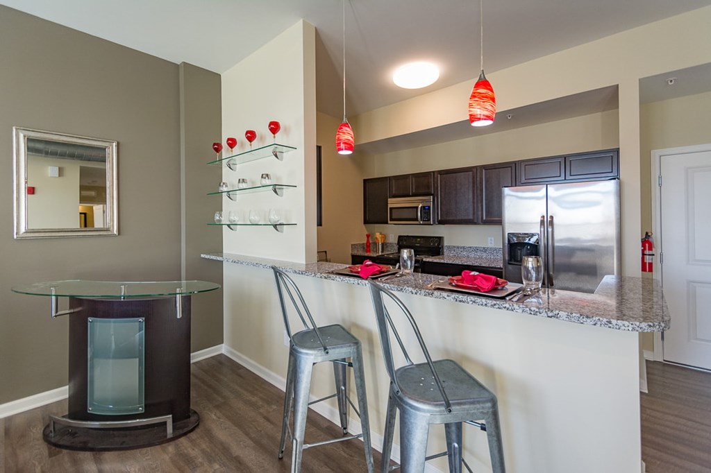 A kitchen with a bar stool and a glass table.