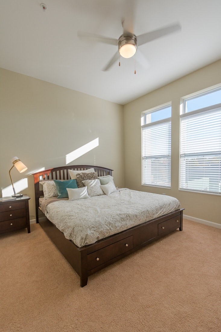 A bedroom with a bed, nightstands, and a ceiling fan.