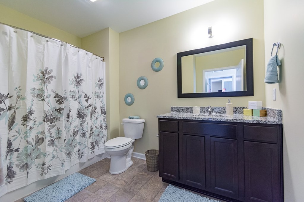 A bathroom with a toilet, sink, and shower curtain.