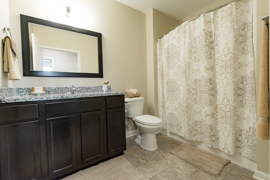 A bathroom with a toilet, sink, and shower curtain.