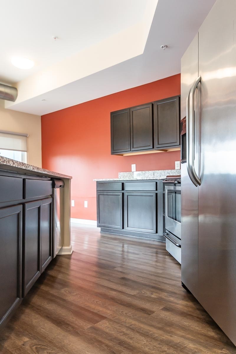 A kitchen with a stainless steel refrigerator and wooden floors.