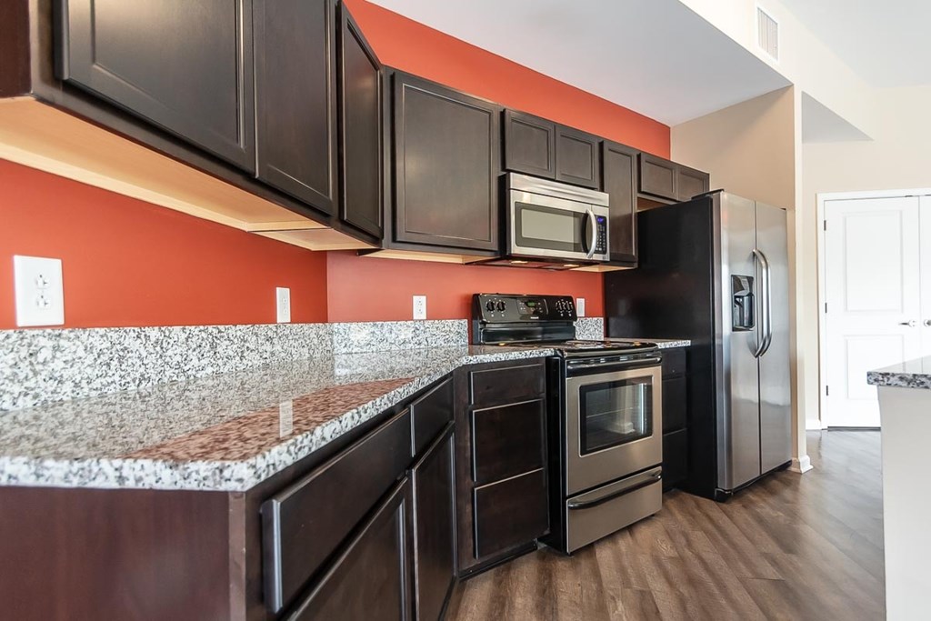 A kitchen with black cabinets and a granite countertop.