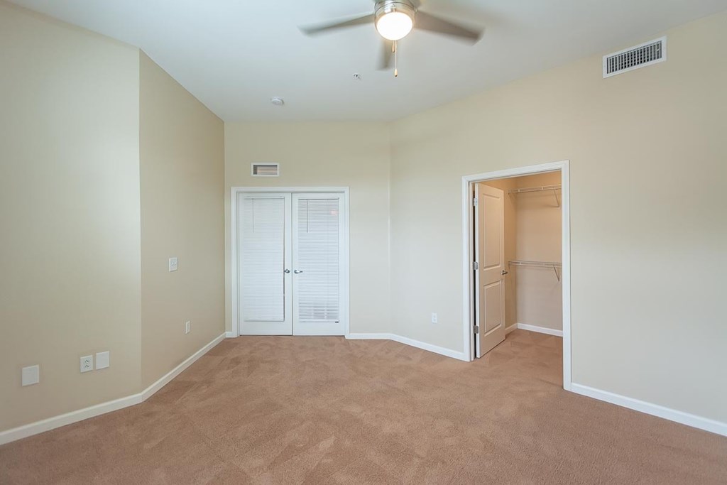 A room with a ceiling fan and carpeted floor.