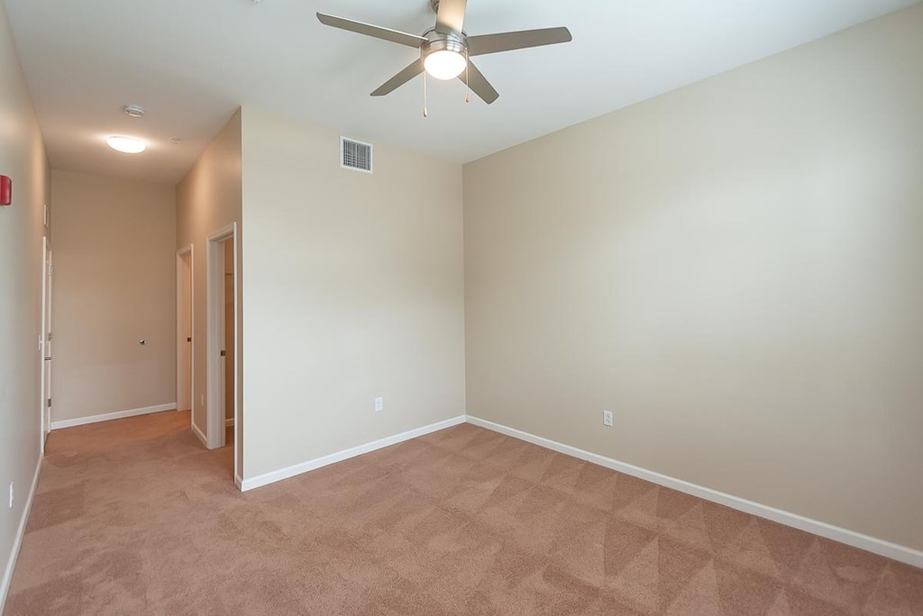 A room with a ceiling fan and carpeted floor.