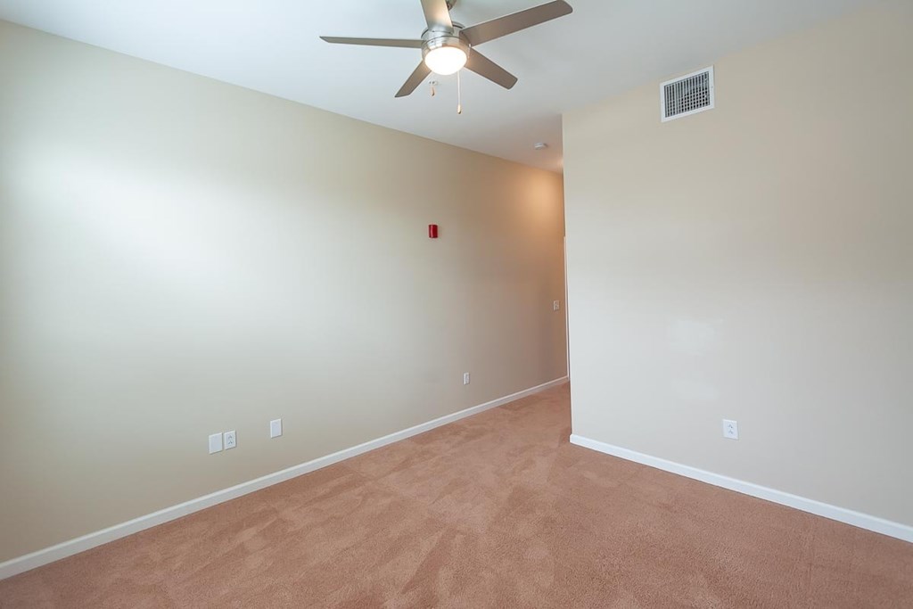 A room with a ceiling fan and carpeted floor.
