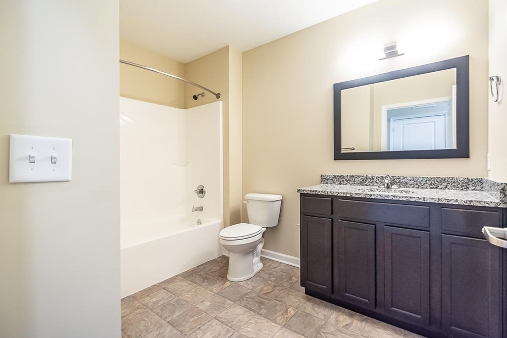 A bathroom with a toilet, sink, and mirror.