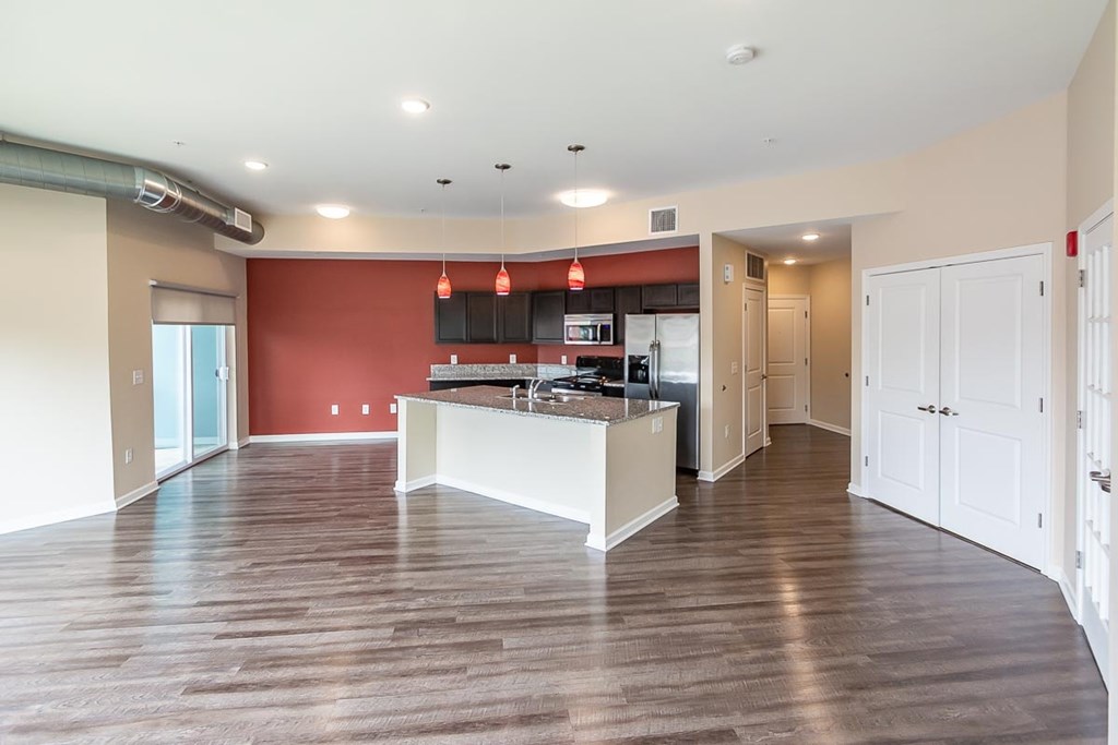 A kitchen with a red wall and white cabinets.