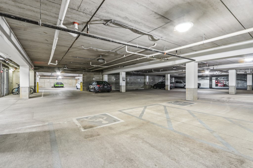 A parking garage with a few cars and a bicycle.