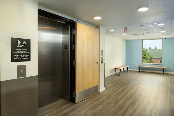 a large wooden door in a room with a window and a bench