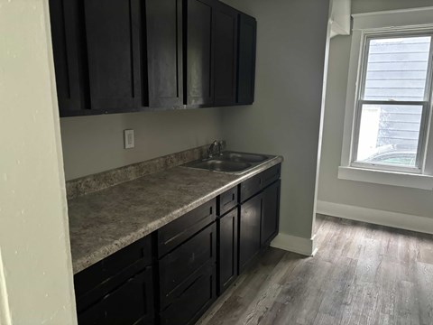 A kitchen with black cabinets and a marble countertop.