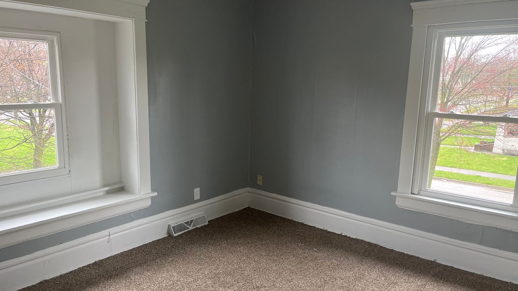 a corner of a room with two windows and a carpet