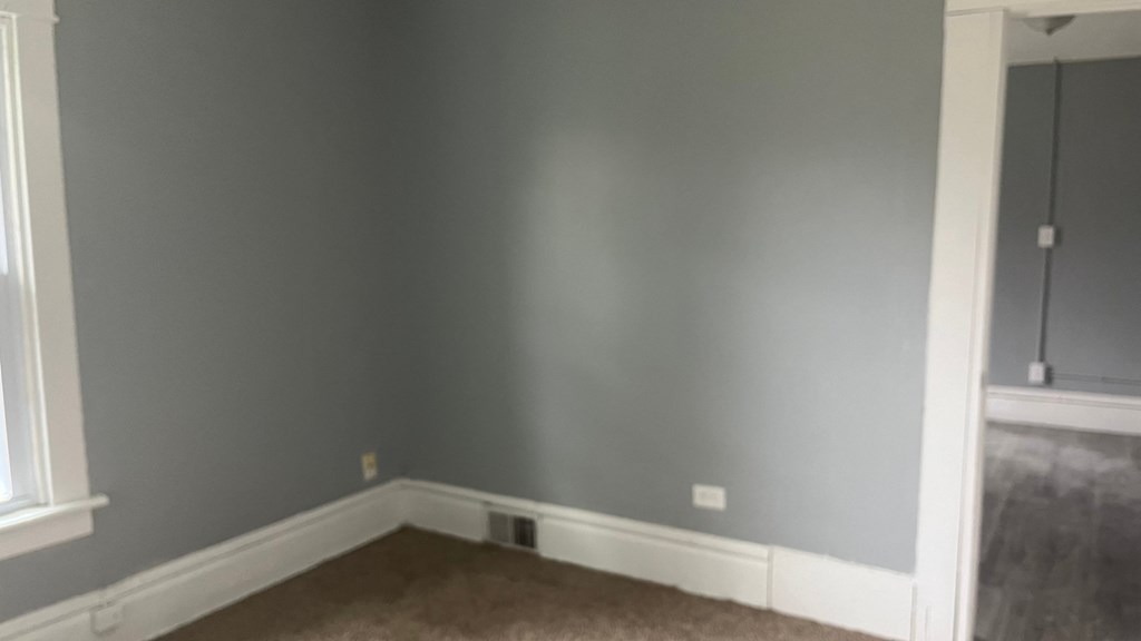an empty room with gray walls and a white baseboard