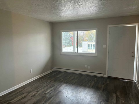 an empty living room with wood floors and a window