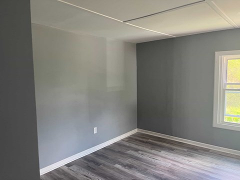 A room with a window and a grey wall.