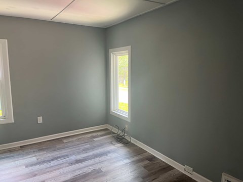 A room with a window and a wooden floor.