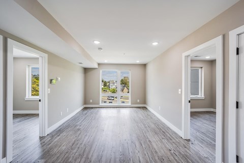 A spacious room with wood flooring and white walls.