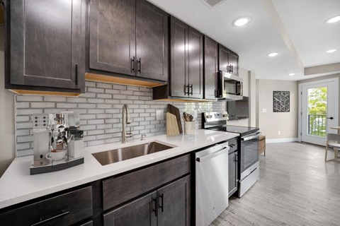 A kitchen with dark wood cabinets and a white countertop.