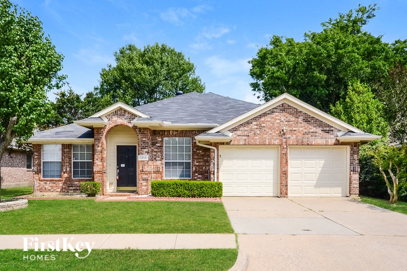 a brick house with two garage doors and a lawn