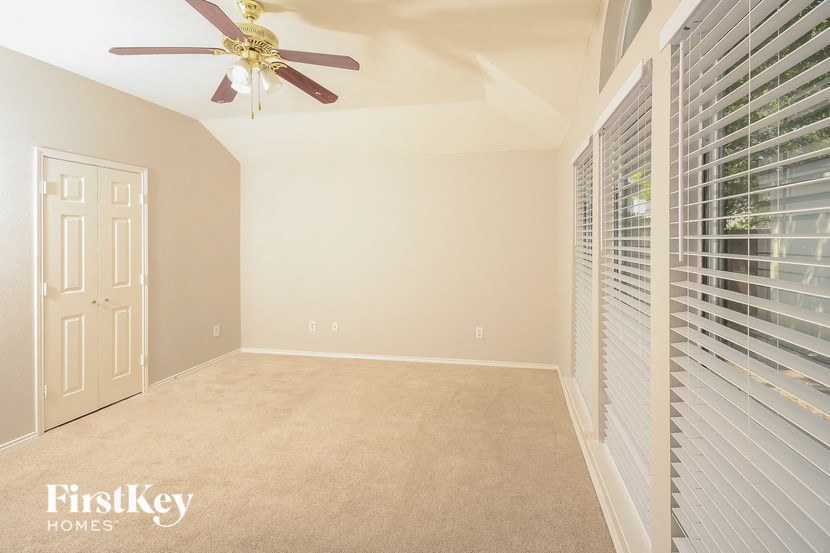 a empty bedroom with a ceiling fan and blinds