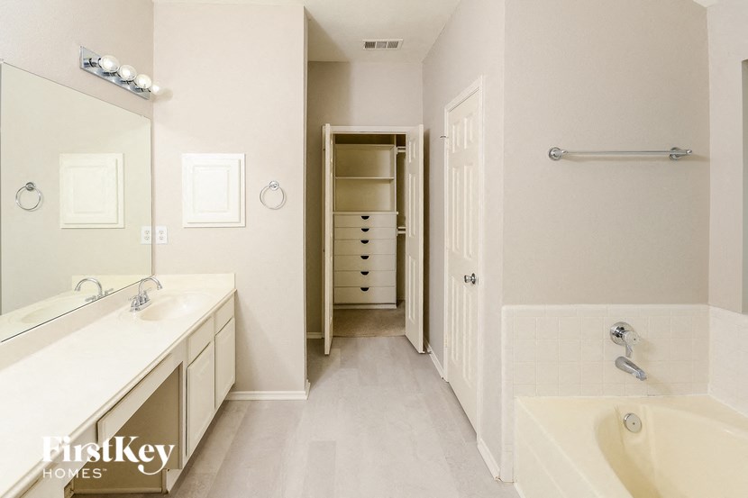a bathroom with two sinks and a tub and a walk in closet