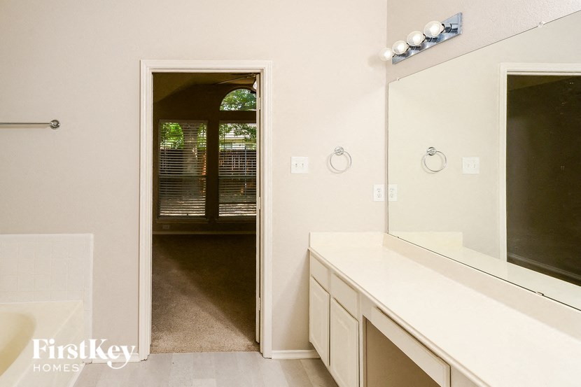 a bathroom with a large mirror and a door to a hallway