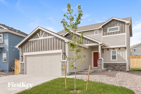 a house with a garage and a tree in front of it