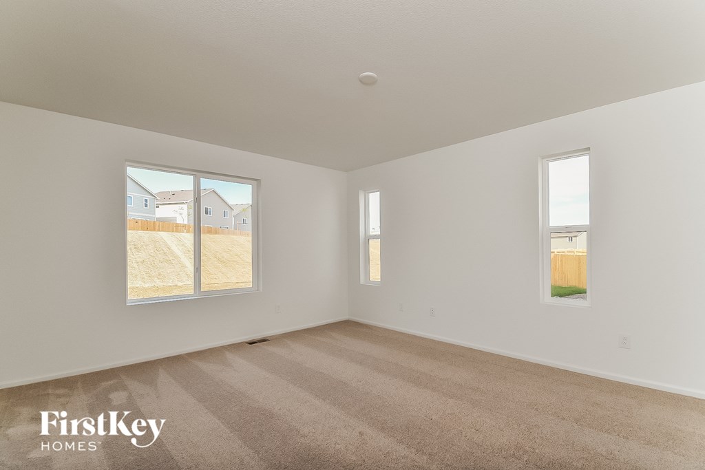 a spacious living room with carpet and two windows