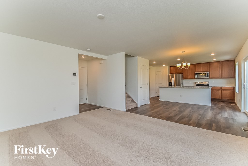 an empty living room and kitchen with white walls and wood flooring