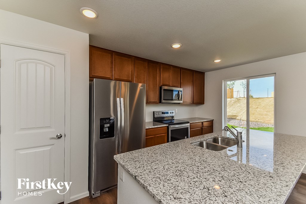 a kitchen with granite counter tops and a stainless steel refrigerator