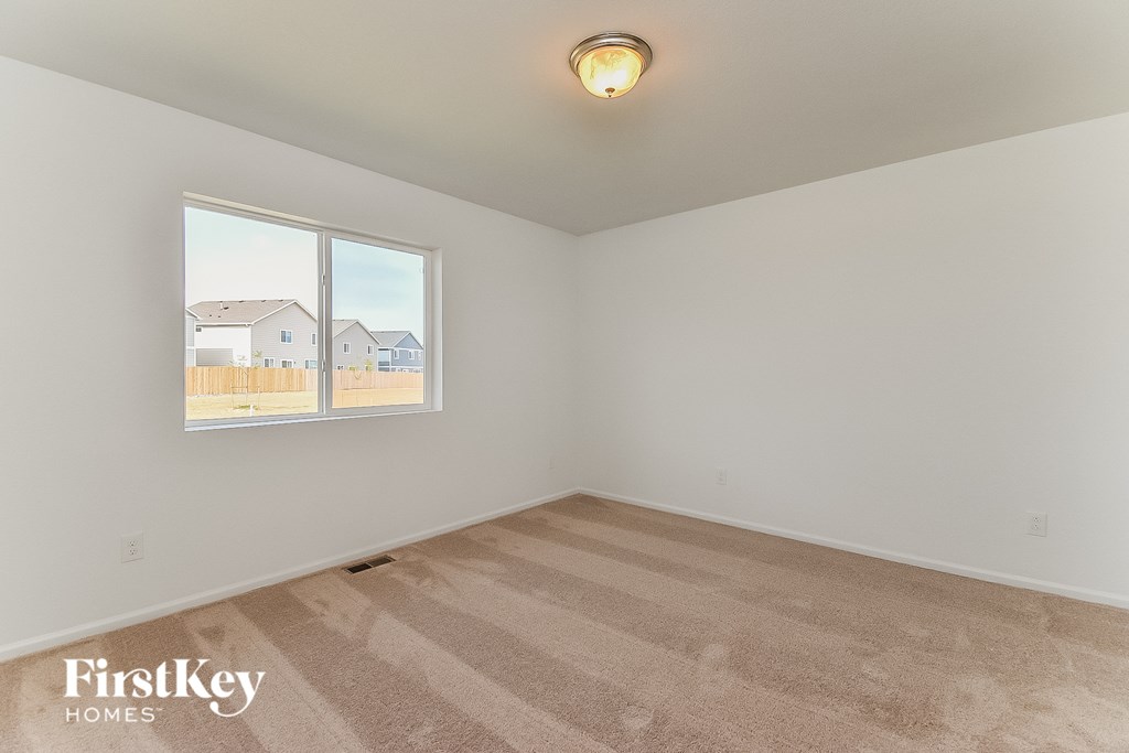 the living room of a home with a large window and beige carpet