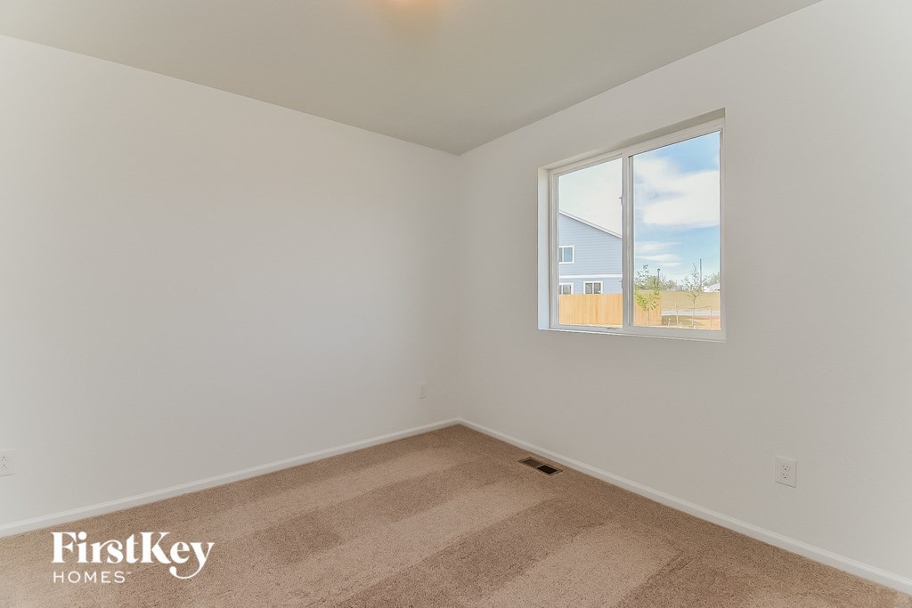a bedroom with a large window and white walls