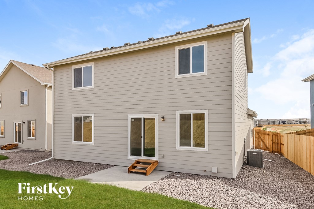 the back of a house with a gravel driveway and grass