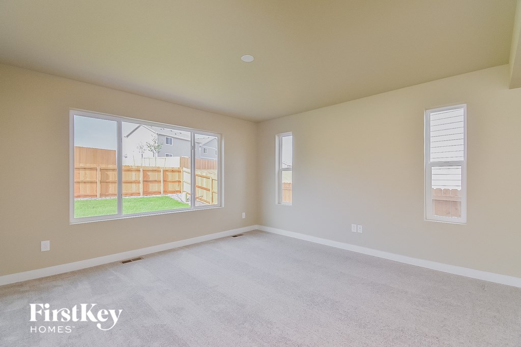 a spacious living room with a large window and white carpet