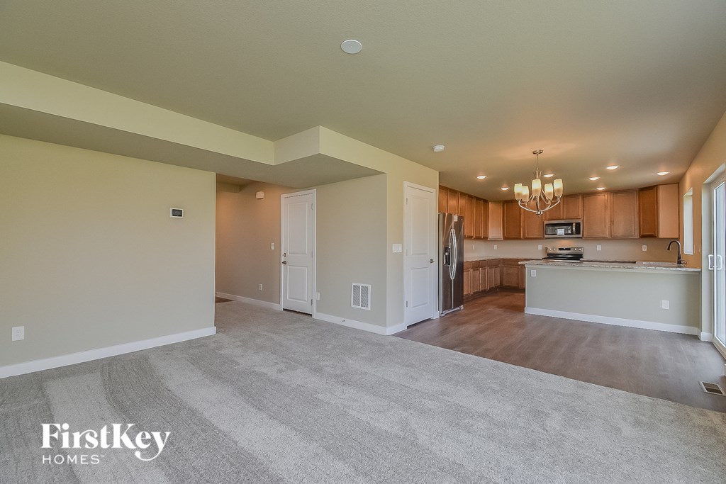 an empty living room and kitchen with white walls and wood cabinets