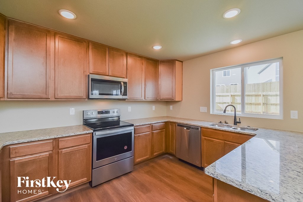 a kitchen with wooden cabinets and granite counter tops and a sink and a window