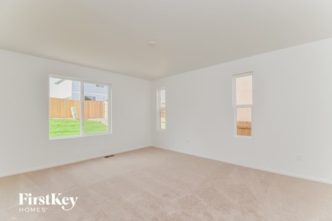 a spacious living room with white walls and a window