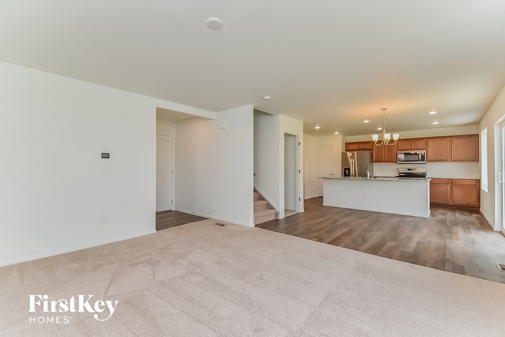 an empty living room and kitchen with white walls and wood flooring